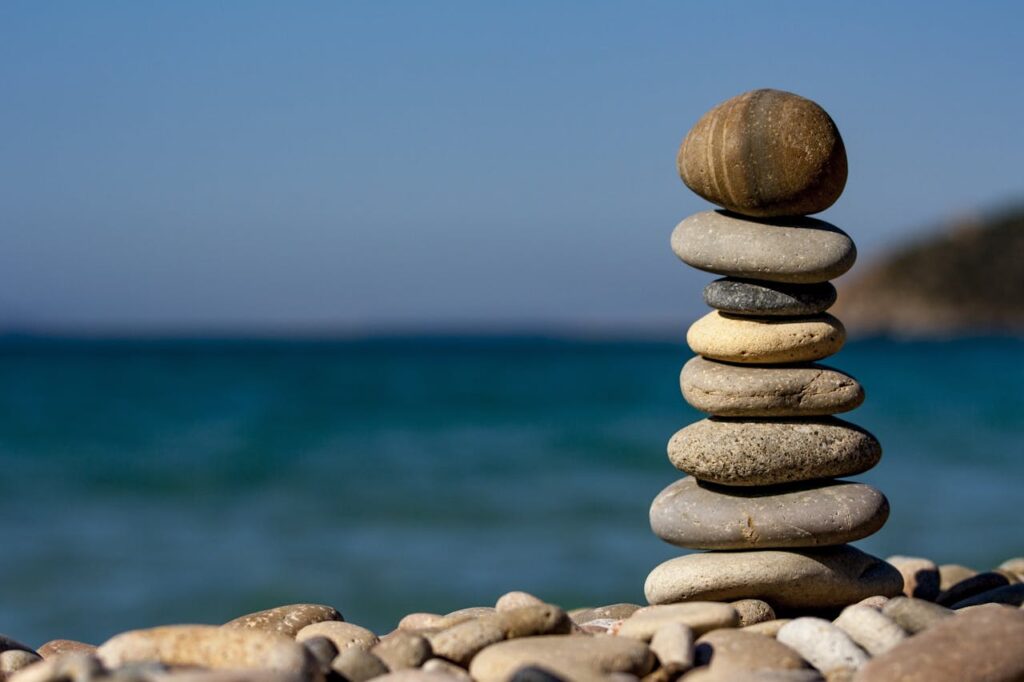pexels-photo-235990 A stack of balanced stones on a beach with a tranquil ocean backdrop for meditation and zen.